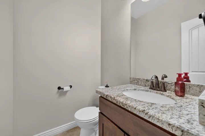 Granite-style countertop with an undermount sink, wood-finish vanity cabinetry, and a bronze-finish faucet