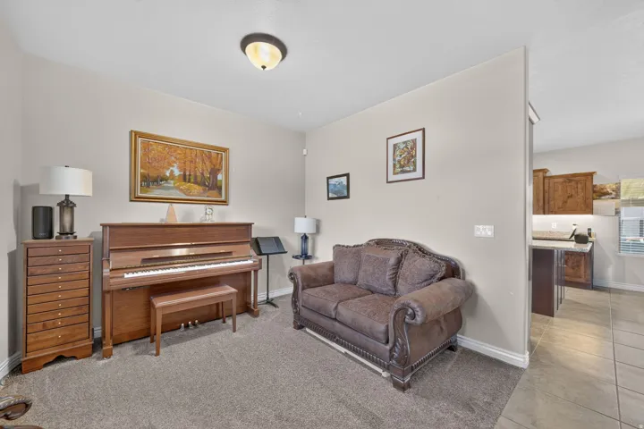 Carpeted flooring, neutral wall tones, semi-flush mount ceiling light, tiled flooring in adjacent area, wood-finish cabinetry visible in adjacent area