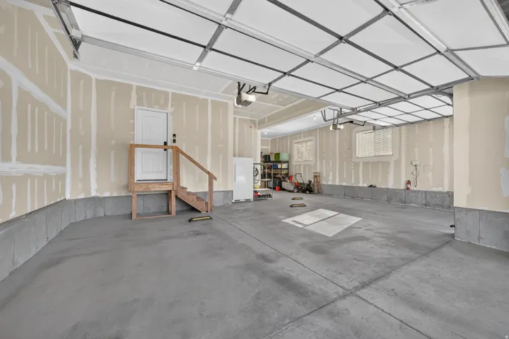 Expansive concrete flooring garage with multiple windows and a utility door
