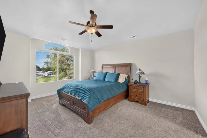 Arched window with blinds, ceiling fan with integrated lighting, and neutral wall tones