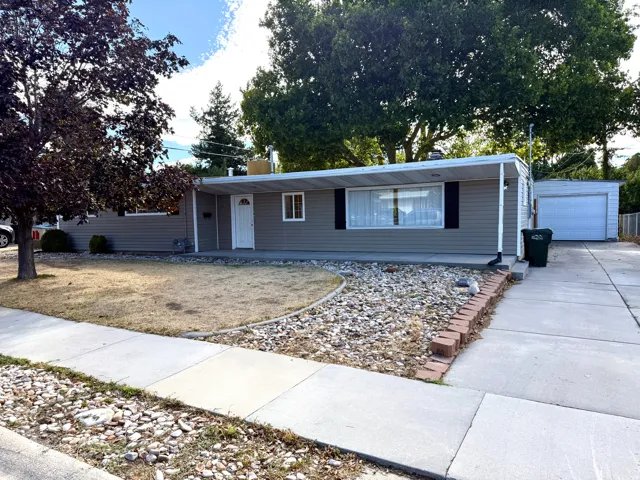 Single-level residence featuring gray siding, a covered entry, and a detached garage