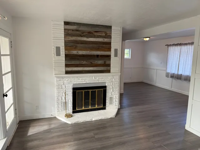 White brick fireplace with a wood-finish accent wall and a dark bronze firebox