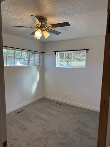 White walls with textured ceiling and a ceiling fan light fixture