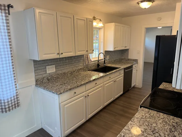 Modern kitchen featuring white cabinetry, speckled countertops, a subway tile backsplash, and wood-finish flooring