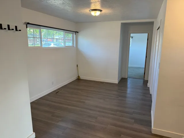 Open area featuring wood-finish flooring, white walls, and a multi-pane window