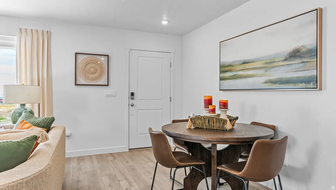 White interior walls, wood-finish flooring, recessed lighting, and a solid panel door