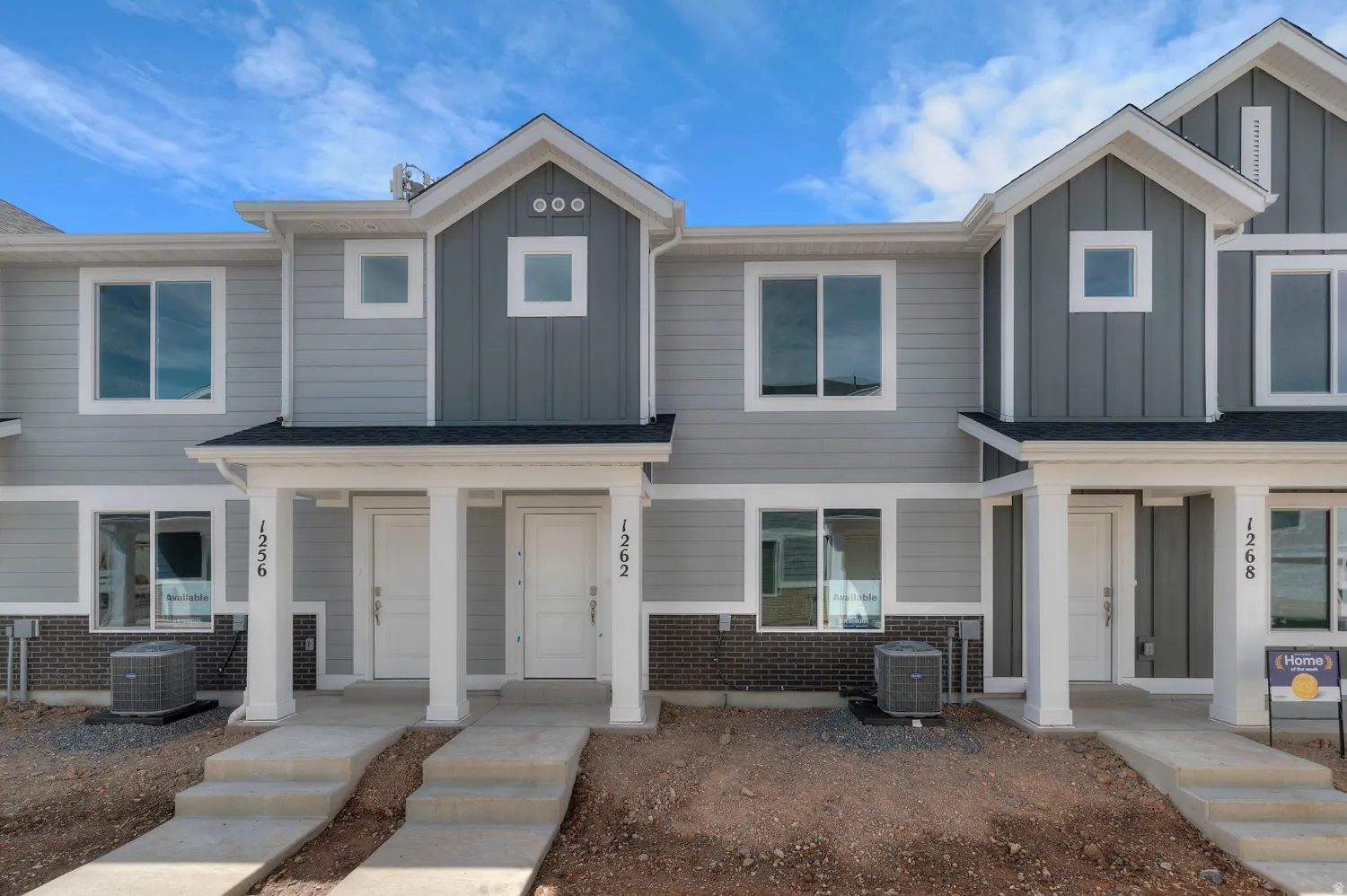Contemporary townhome with light gray siding, dark gray vertical accent siding, white trim, and a dark shingled roof