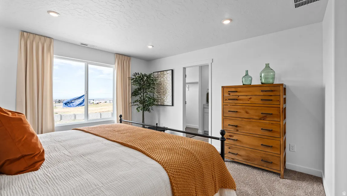 Carpeted bedroom featuring a large window, recessed lighting, and a built-in closet with shelving