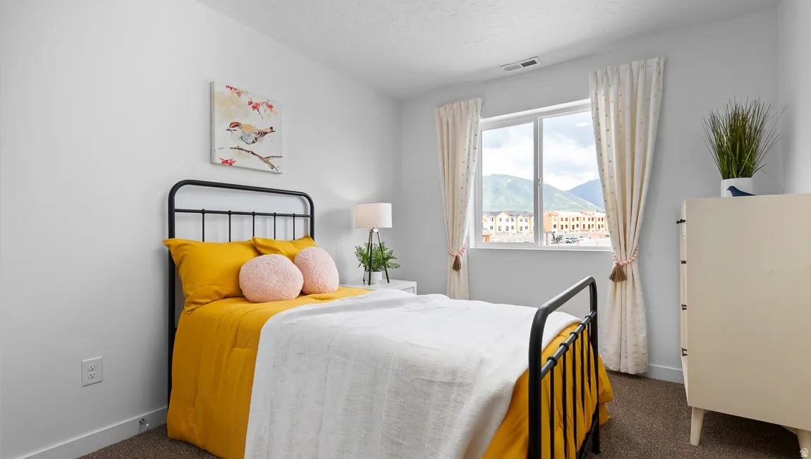 Neutral wall paint, carpeted flooring, and a large window with a distant mountain backdrop