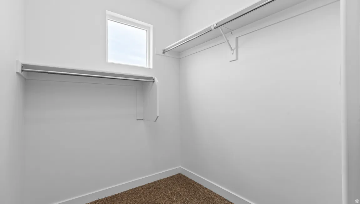 Walk-in closet featuring a window, built-in shelving, and hanging rods