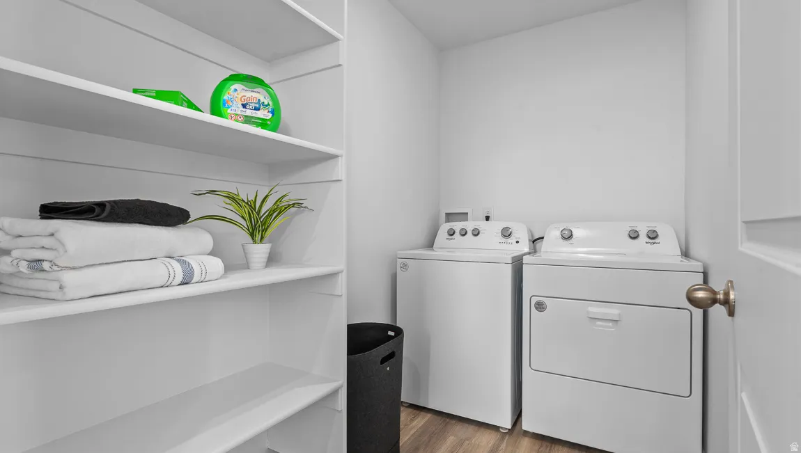 Laundry area with built-in shelving, wood-finish flooring, and a solid panel door with bronze hardware