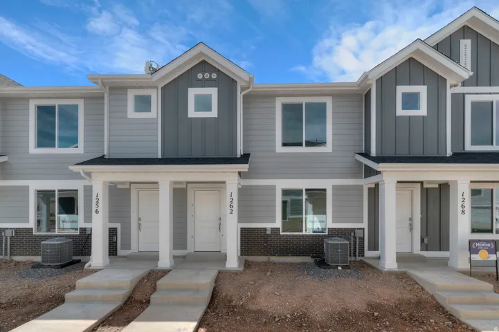 Contemporary townhome with light gray siding, dark gray vertical accent siding, white trim, and a dark shingled roof