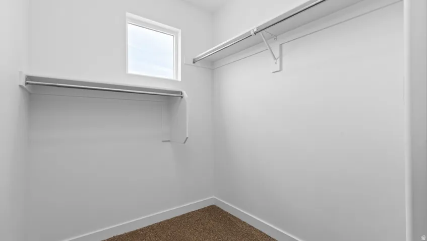 Walk-in closet featuring a window, built-in shelving, and hanging rods
