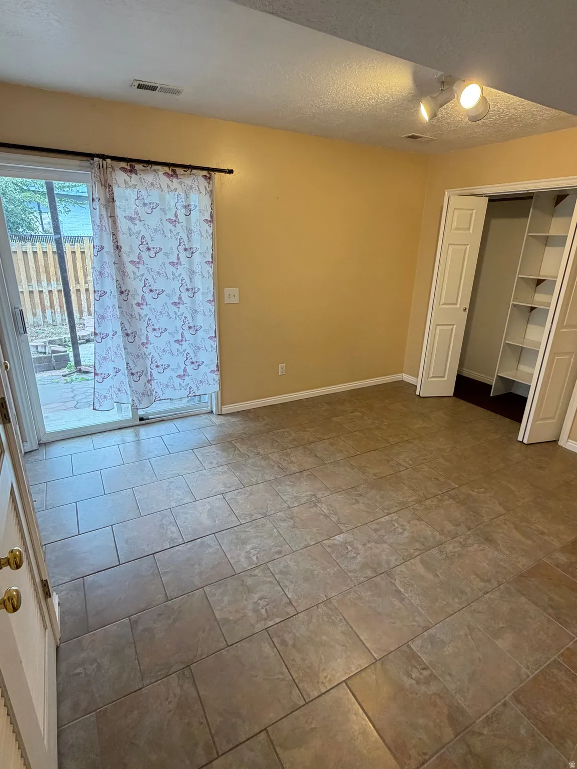 Tiled flooring, track lighting, sliding glass door, built-in shelving