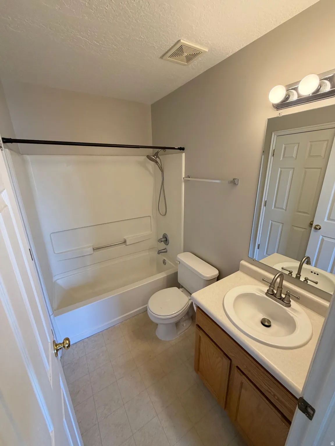 Full bathroom featuring a single vanity with a laminate countertop, an integrated sink, a built-in bathtub with shower, and vinyl flooring