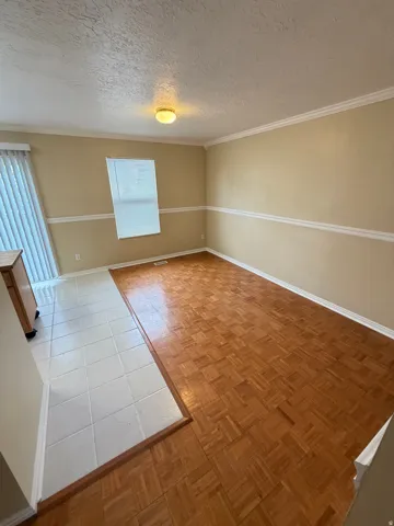 Parquet wood flooring, tile flooring, crown molding, chair rail molding, and a built-in light fixture
