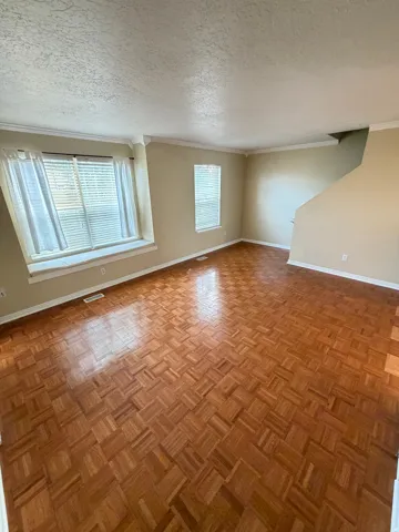 Parquet wood-finish flooring, multiple windows, crown molding, and a window seat