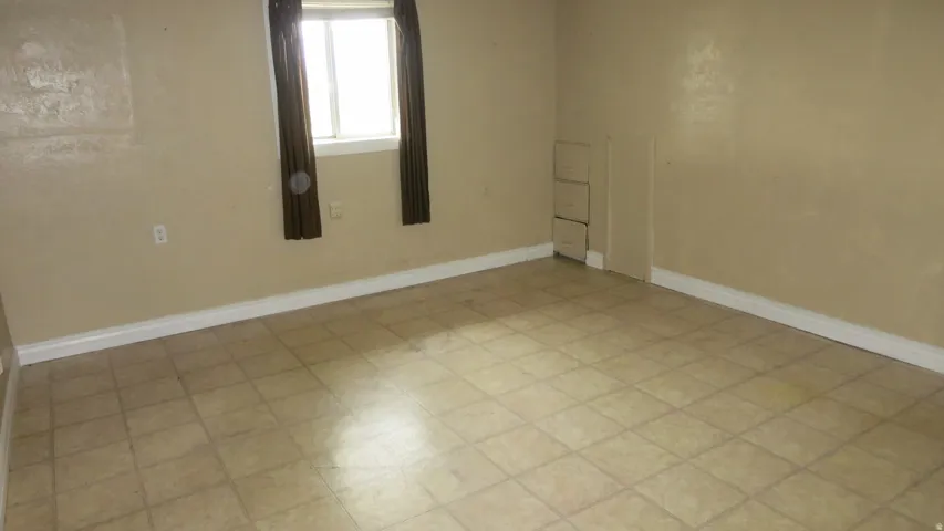 Tiled flooring with a neutral finish, white baseboards, and a window with natural light