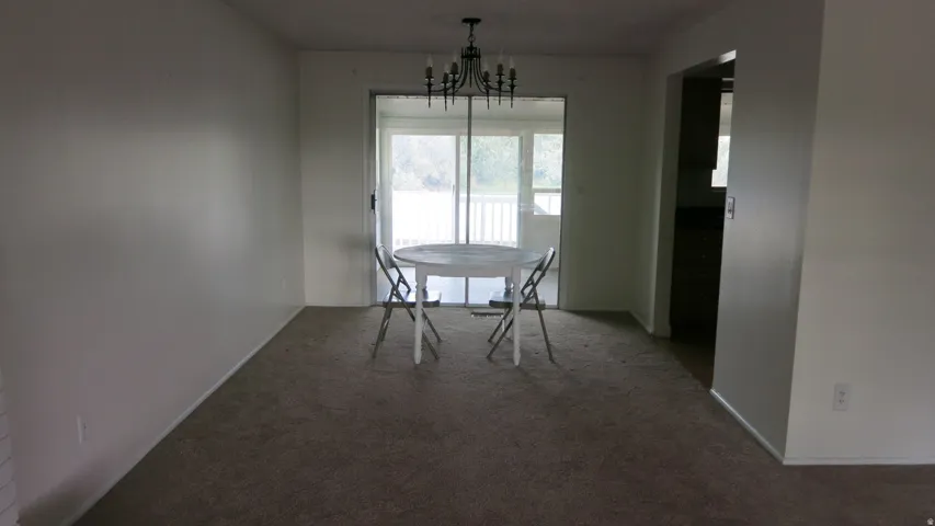 Dining area featuring carpet flooring, a chandelier fixture, and direct access to an enclosed porch through a sliding glass door