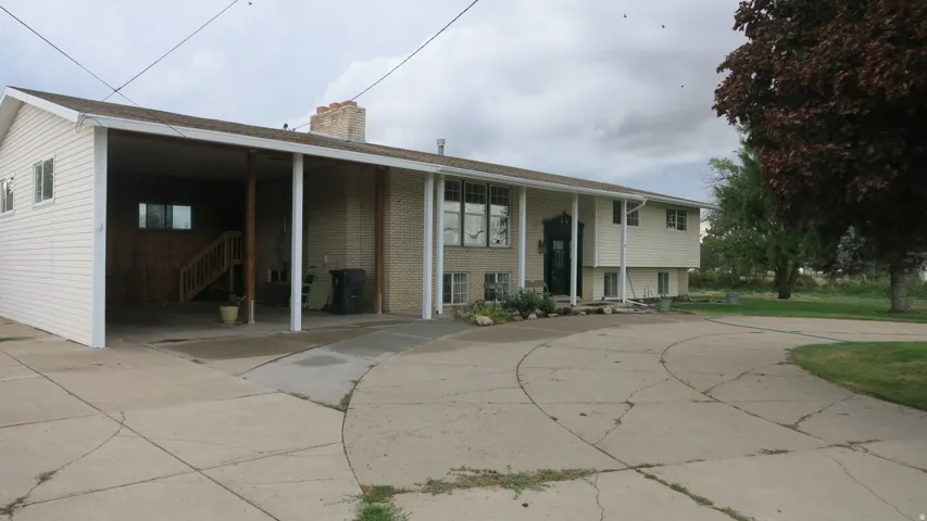 Split-level residence featuring a covered carport, brick facade accents, and a front entry with decorative columns