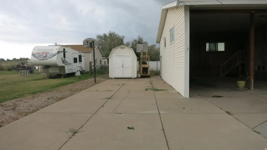 Concrete driveway leading to a detached storage shed and an open-sided carport structure
