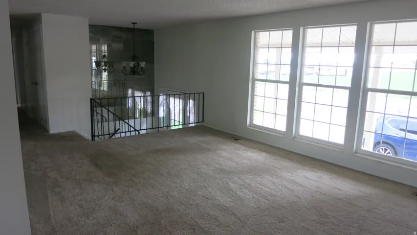 Wall of three large grid-pattern windows, open railing, and a decorative wall with a suspended chandelier