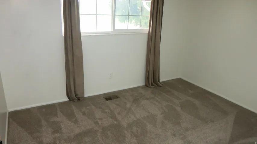 Expansive room with neutral carpeting and a large window
