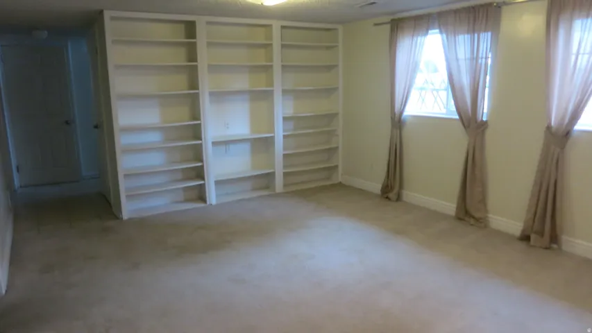 Built-in shelving, two windows, wall-to-wall carpeting, and baseboard trim