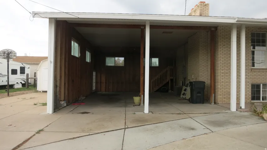 Covered carport featuring a concrete driveway and exposed wood beams