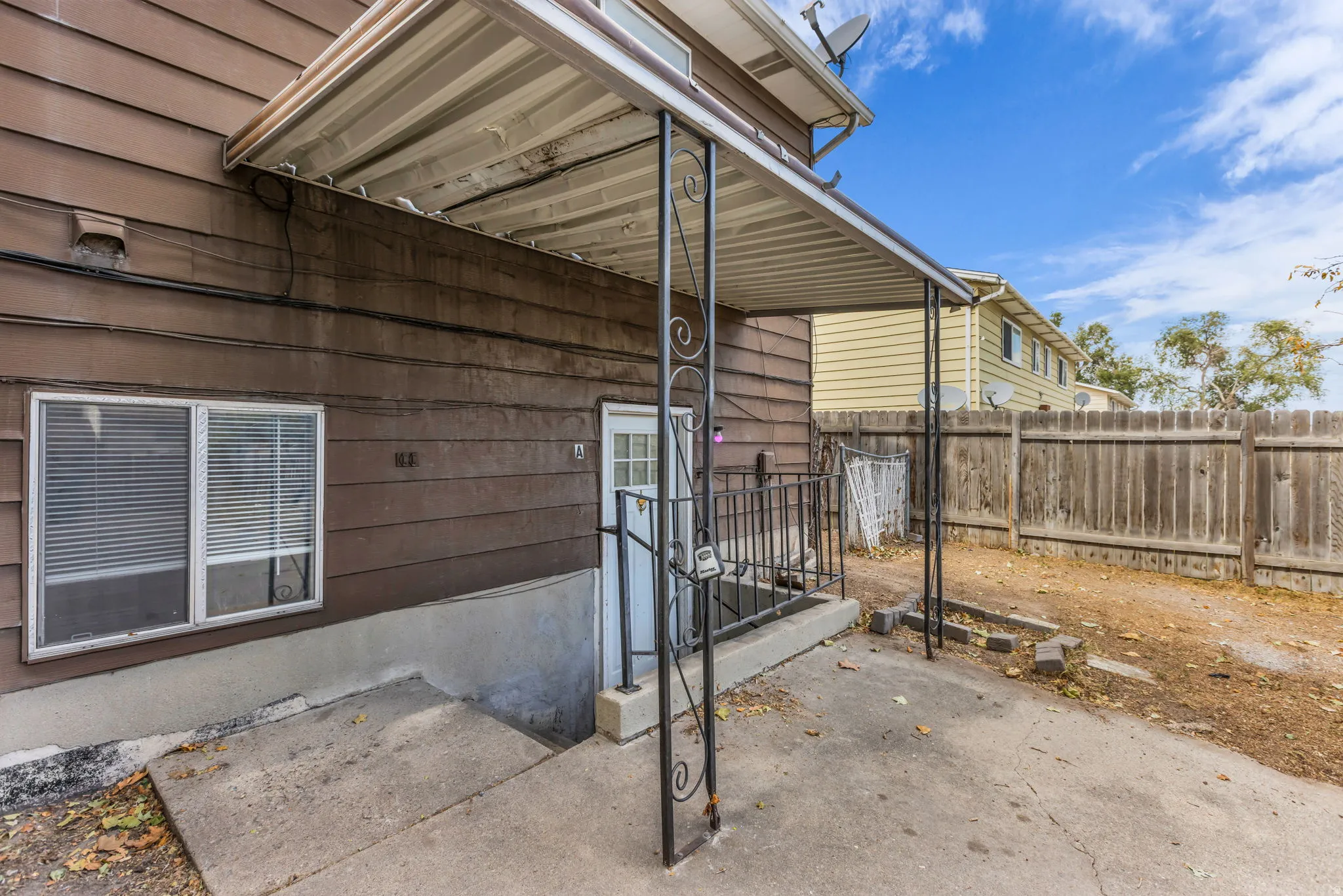Attached covered patio with concrete flooring, leading to a fenced yard