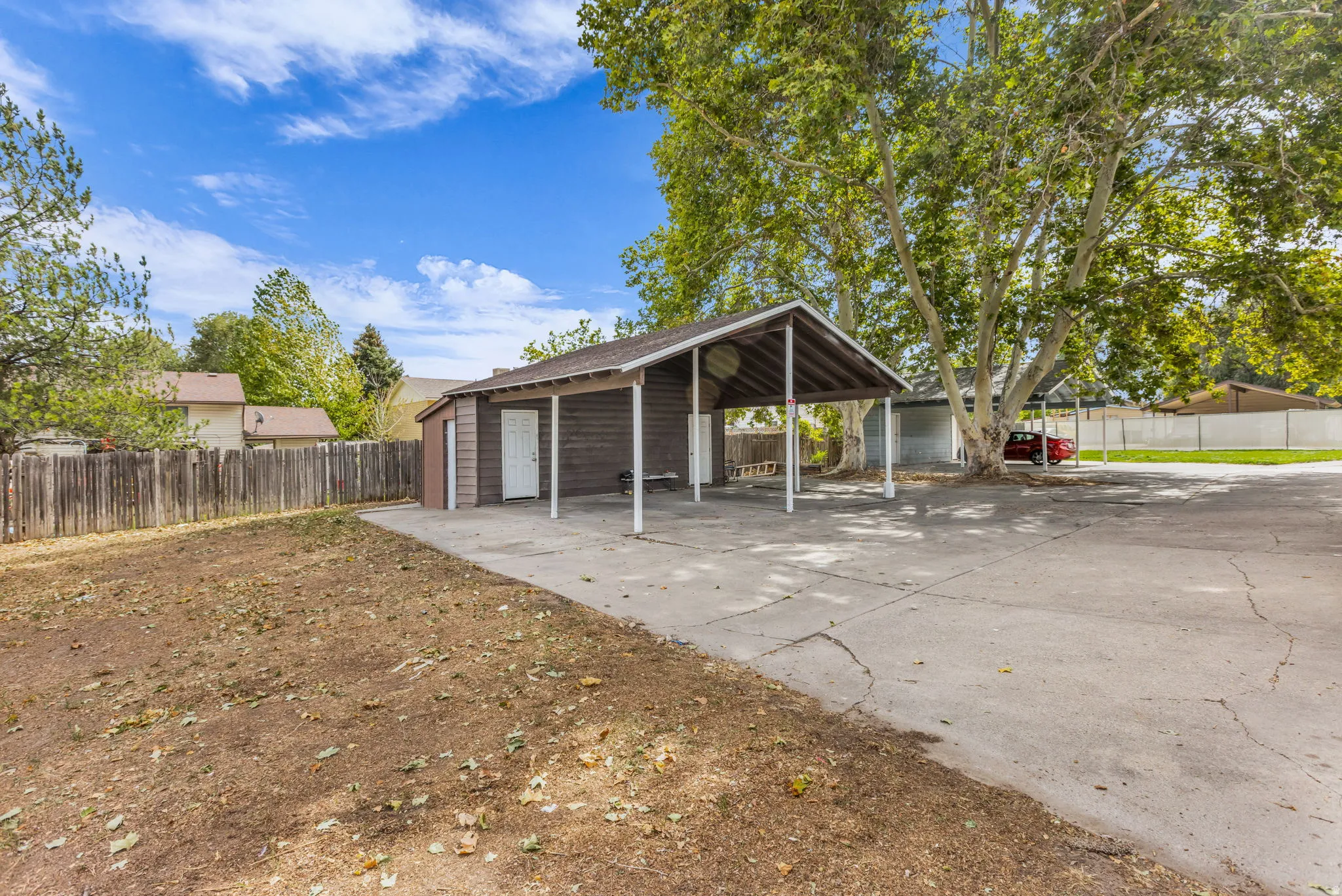 Paved carport with an adjacent shed and a privacy fence