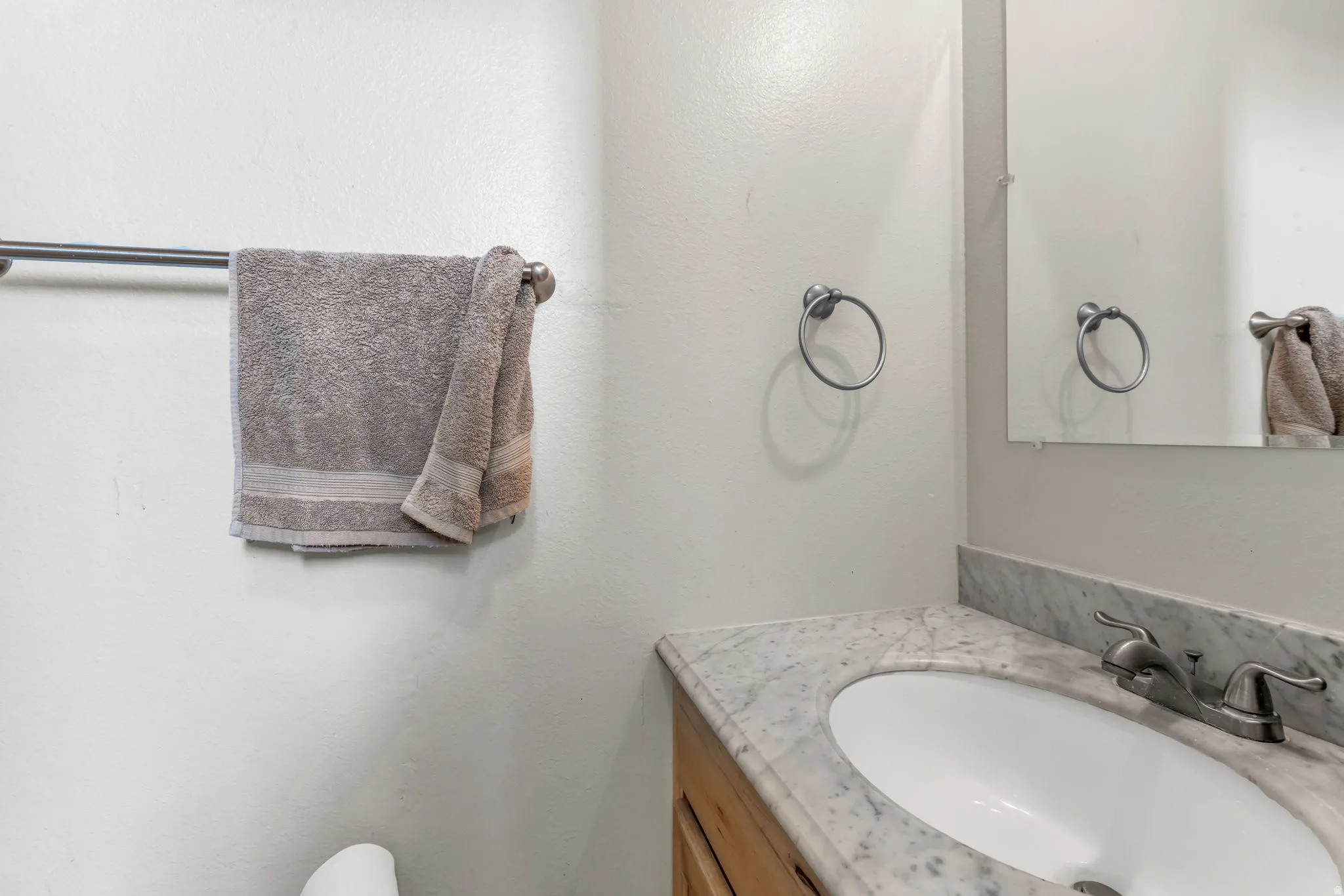 Vanity with an integrated oval sink, stone countertop, and a wall-mounted mirror