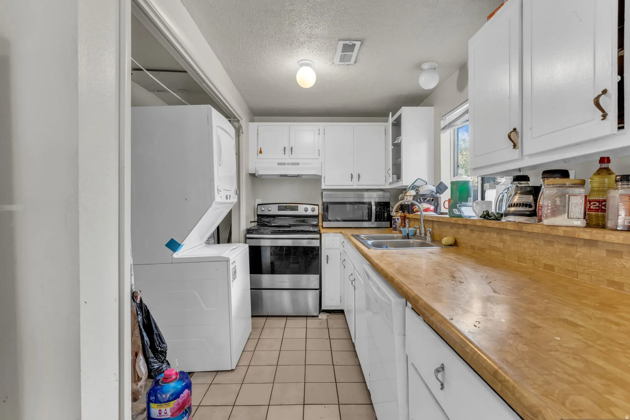 Unit B, Compact kitchen featuring wood-finish countertops, white cabinetry, a stainless steel range, and tile flooring