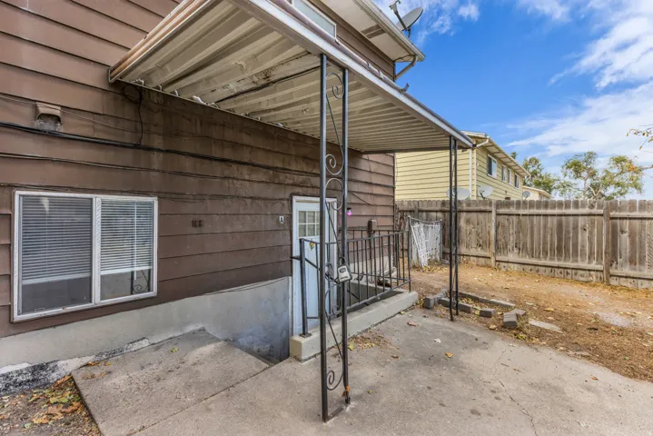 Attached covered patio with concrete flooring, leading to a fenced yard