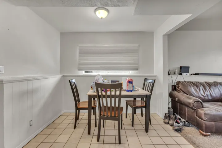 White paneled wainscoting, neutral tile flooring, and a window with blinds