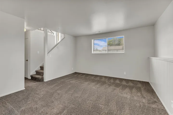 Carpeted flooring, white interior paint, window with blinds, white wainscoting, and carpeted stairs