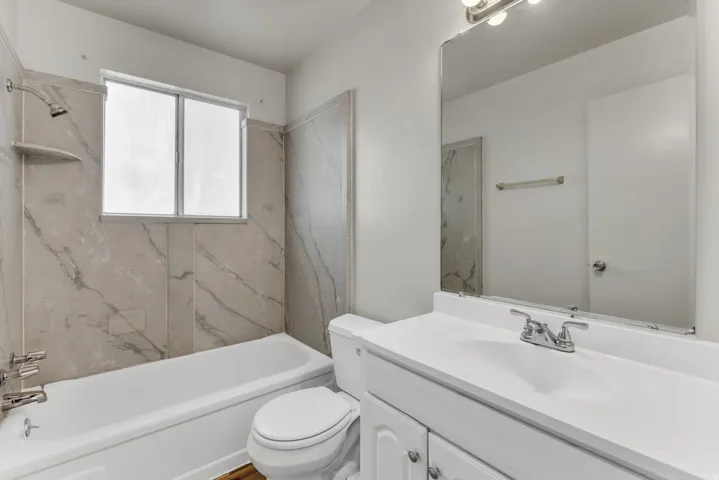 White vanity with an integrated sink, polished chrome faucet, and mirrored light fixture