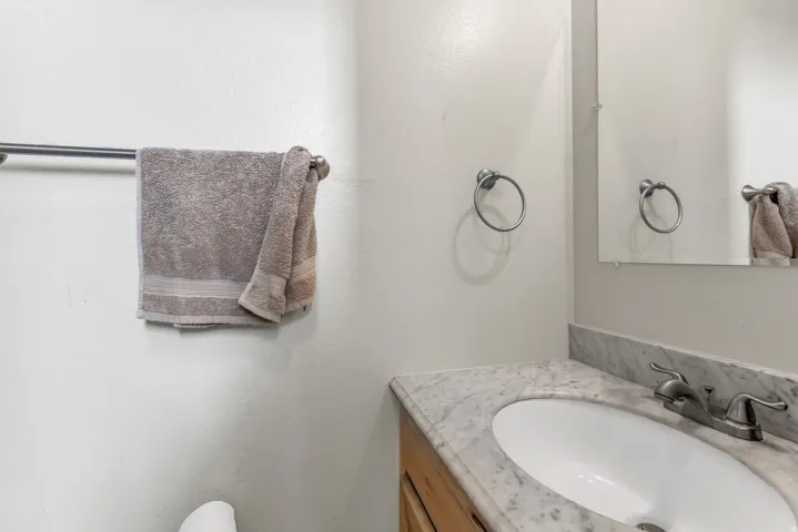 Vanity with an integrated oval sink, stone countertop, and a wall-mounted mirror