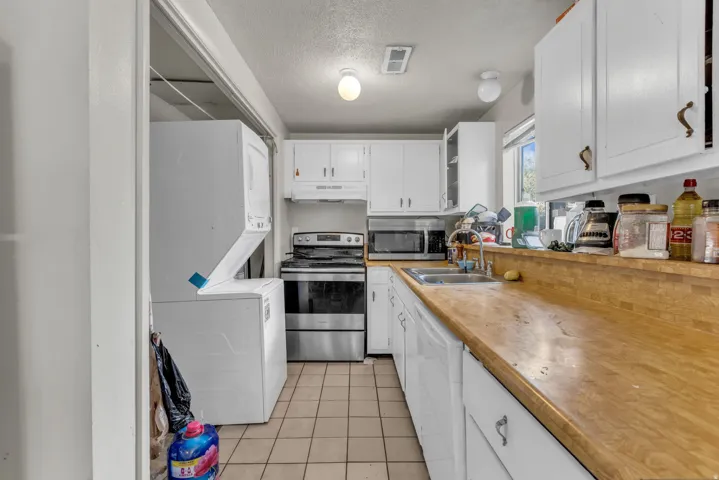Unit B, Compact kitchen featuring wood-finish countertops, white cabinetry, a stainless steel range, and tile flooring