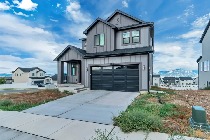 Two-story residence featuring a covered entry, attached two-car garage, and a concrete driveway
