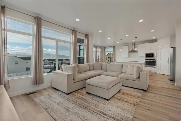 Open-concept living space featuring wood-finish flooring, recessed lighting, and large windows