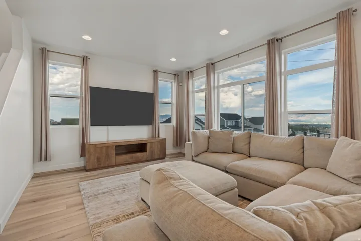 Expansive window wall, recessed lighting, wood-finish flooring, and a built-in media console
