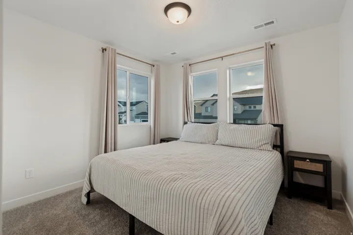 Neutral wall paint, carpet flooring, recessed ceiling light fixture, multiple windows with natural light