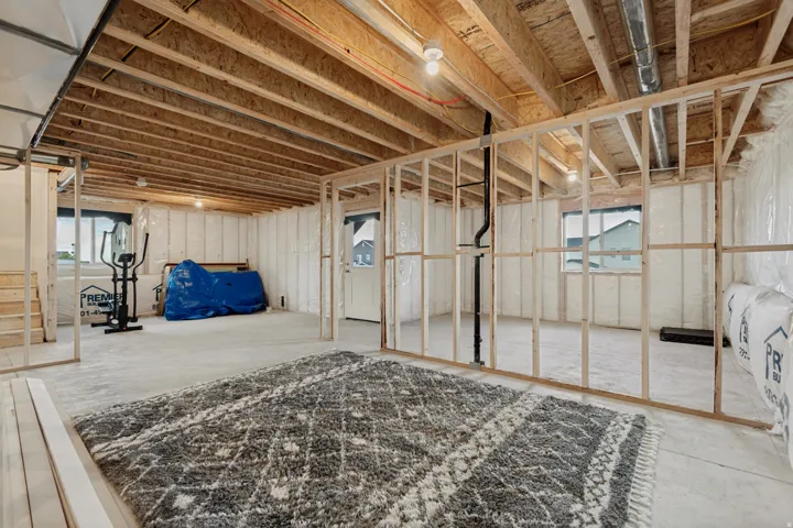 Unfinished lower level featuring exposed wood framing, concrete flooring, and multiple windows providing natural illumination