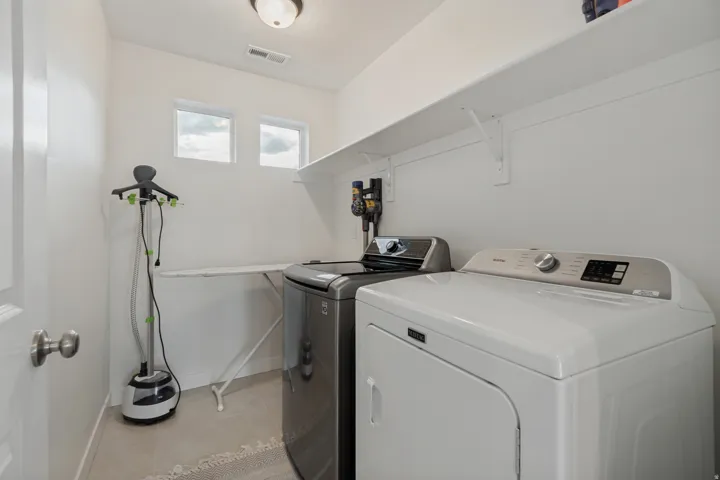 Laundry area featuring a built-in shelf, two windows, and overhead lighting