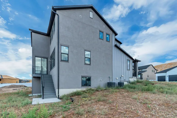 Contemporary exterior with mixed siding, multiple windows, and a sliding glass door leading to exterior stairs
