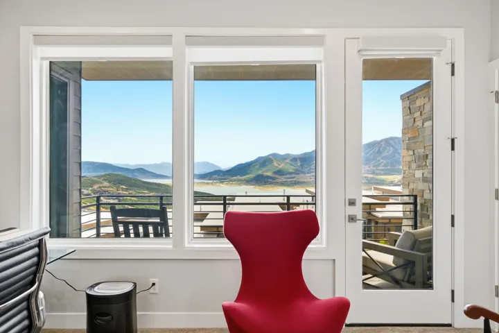 Expansive windows offering mountain scenery, a white-framed glass door, and an exterior balcony with a railing