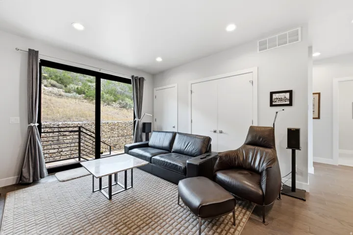 Recessed lighting, wood-finish flooring, white walls, and a glass sliding door