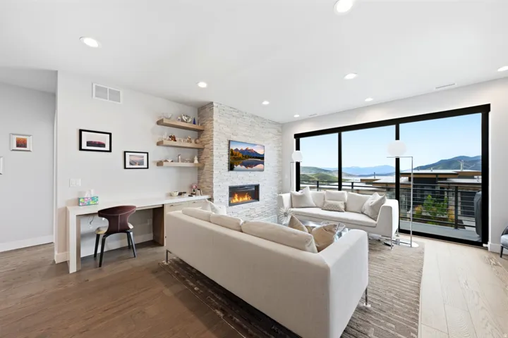 Wood-finish flooring, recessed lighting, built-in desk, stacked stone fireplace, and floor-to-ceiling windows