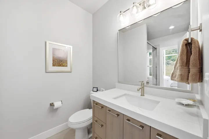Vanity with wood-finish cabinetry, integrated sink, and light-toned countertop